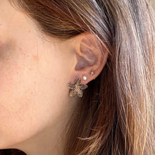 Load image into Gallery viewer, Close-up of a person wearing a star-shaped earring with a neutral background