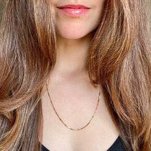 Load image into Gallery viewer, Close-up of a person wearing a gold necklace with long brown hair.