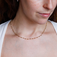 Load image into Gallery viewer, Close-up of a woman wearing a gold necklace with a blurred background