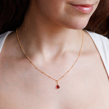 Load image into Gallery viewer, Close-up of a person wearing a delicate gold necklace with a red pendant.