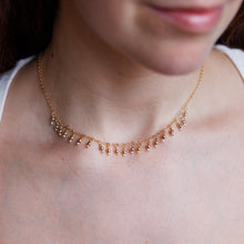 Load image into Gallery viewer, Close-up of a person wearing a delicate gold necklace with a blurred background