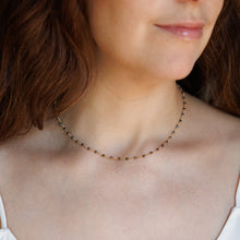 Load image into Gallery viewer, A close-up lifestyle shot of a woman wearing a delicate beaded necklace with small dark beads and tiny gold accents.