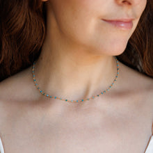 Load image into Gallery viewer, A close-up of a woman wearing a delicate beaded necklace with bright blue gemstone beads.