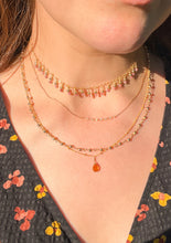 Load image into Gallery viewer, A close-up of a person wearing layered gold necklaces, including a beaded choker, a delicate chain necklace, and a longer necklace with a small citrine teardrop pendant.